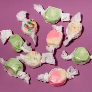 Hometown Hero Live Rosin Taffy candies in assorted pastel colors, individually wrapped and displayed on a purple background.