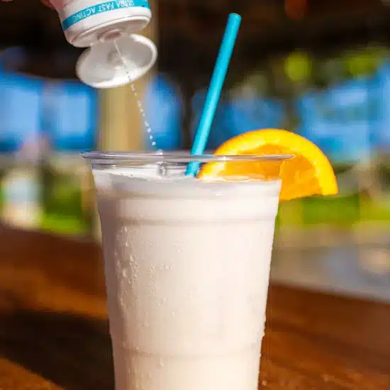 Canna Drops Delta 9 THC Drink Booster being added to a cold citrus drink, showing how the flavorless enhancer blends smoothly into any beverage.